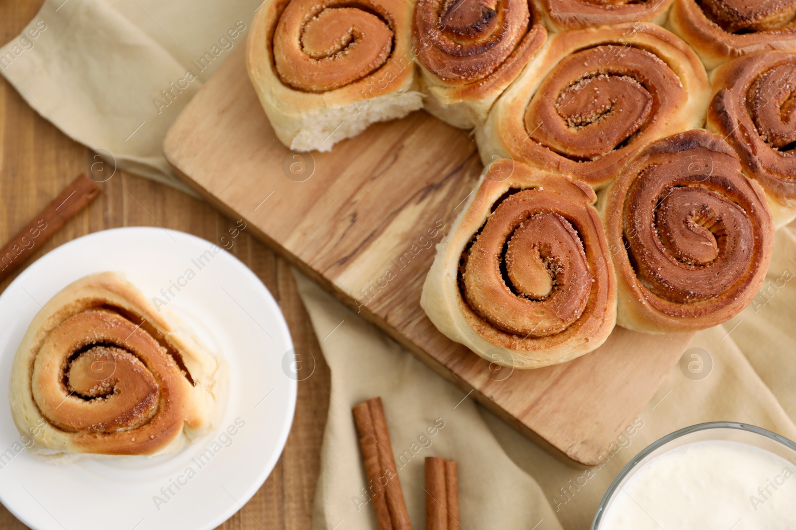 Photo of Freshly baked cinnamon rolls on wooden table, flat lay