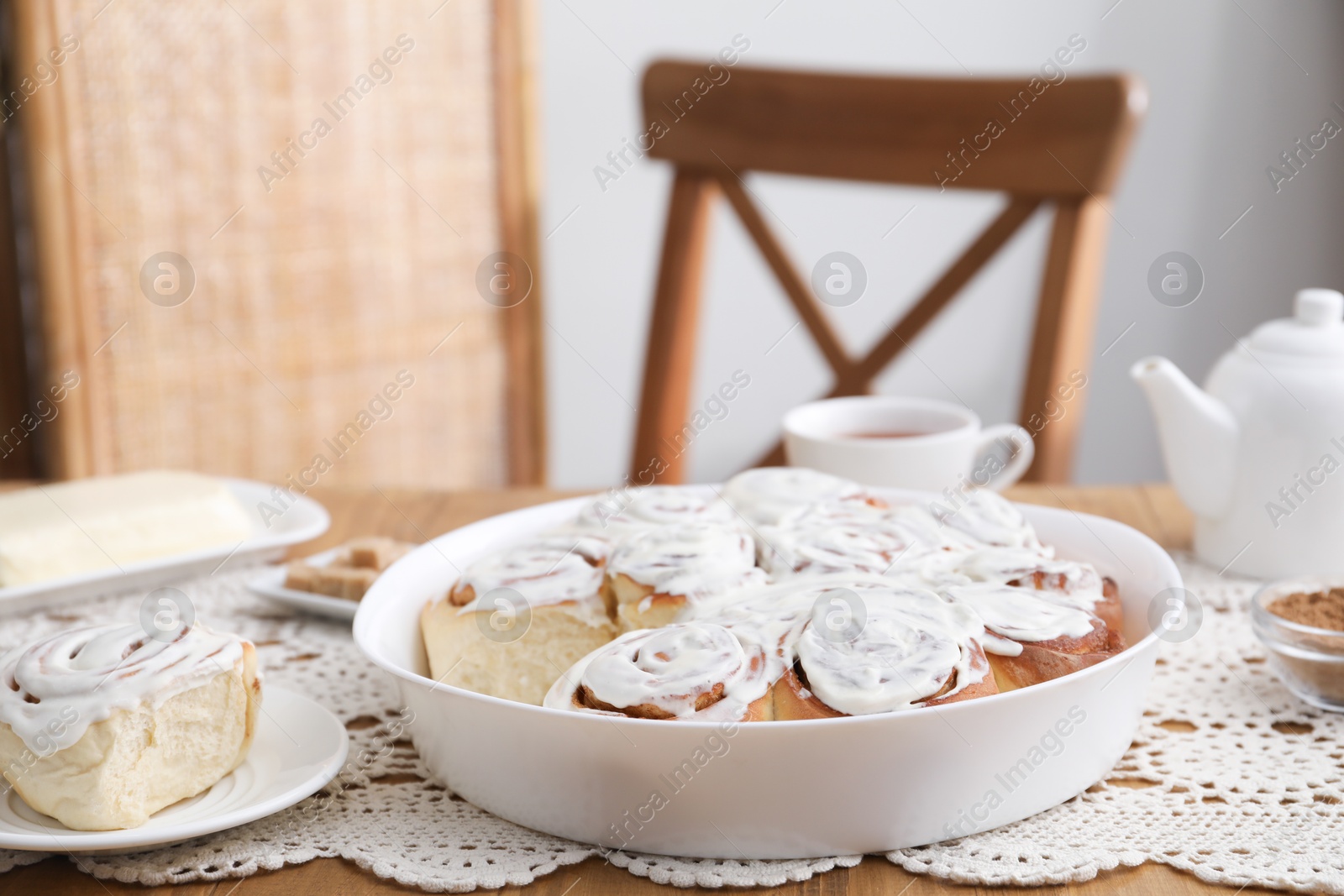 Photo of Delicious frosted cinnamon rolls on wooden table indoors, closeup