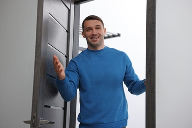 Photo of Cheerful man welcoming guests to his apartment