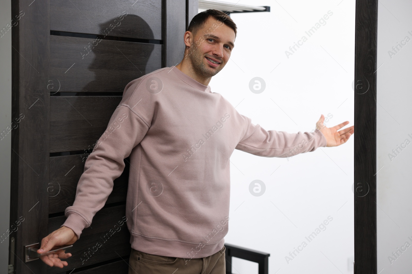 Photo of Cheerful man welcoming guests to his apartment