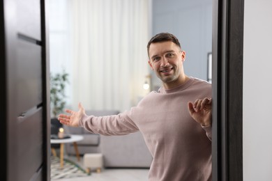 Photo of Cheerful man welcoming guests to his apartment