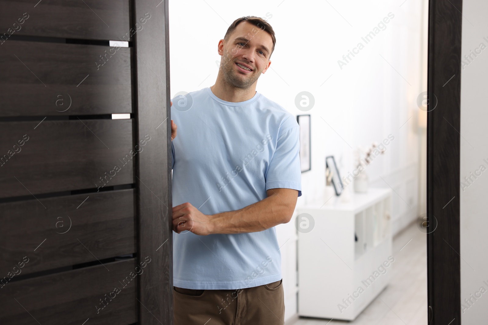 Photo of Cheerful man welcoming guests to his apartment