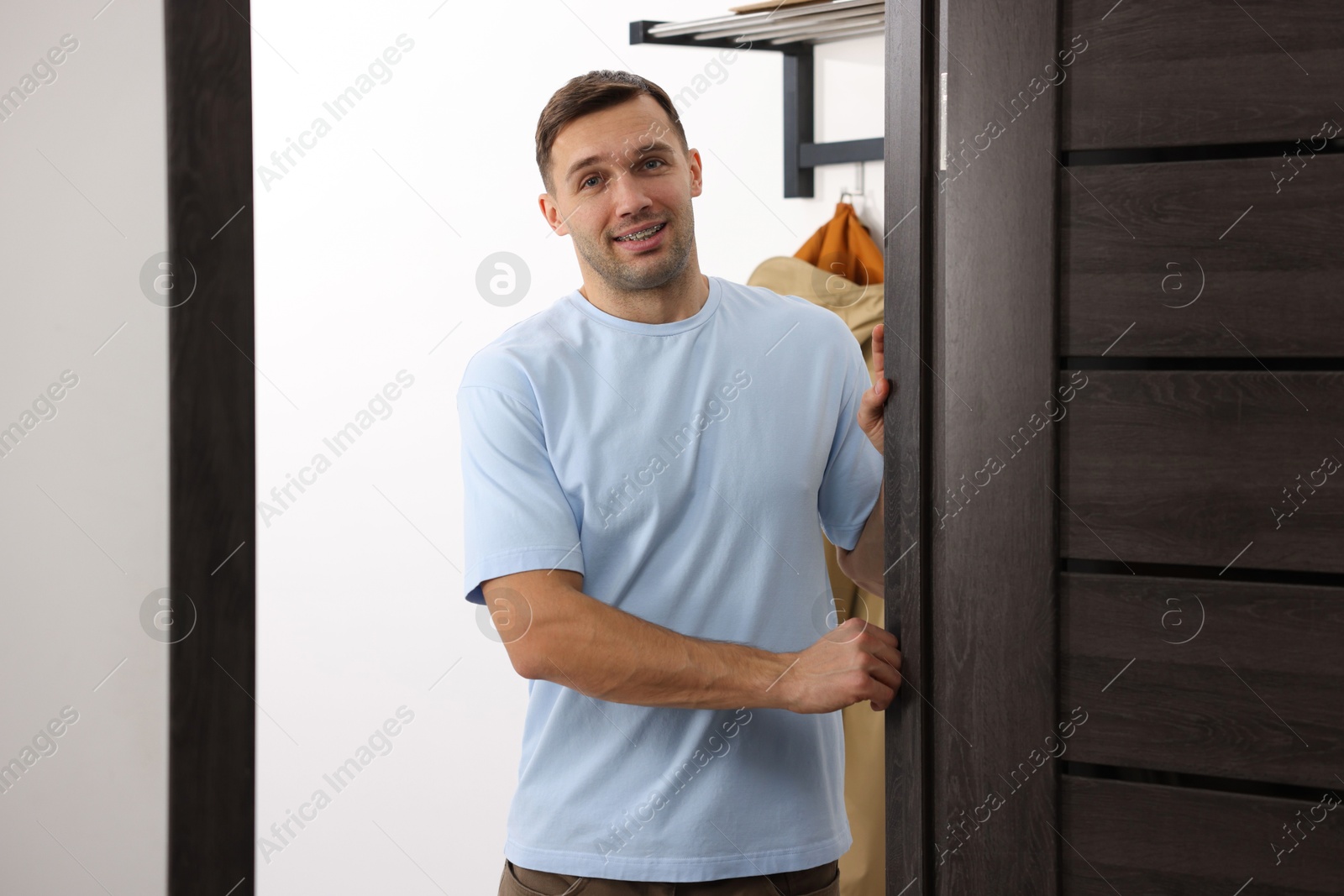 Photo of Cheerful man welcoming guests to his apartment