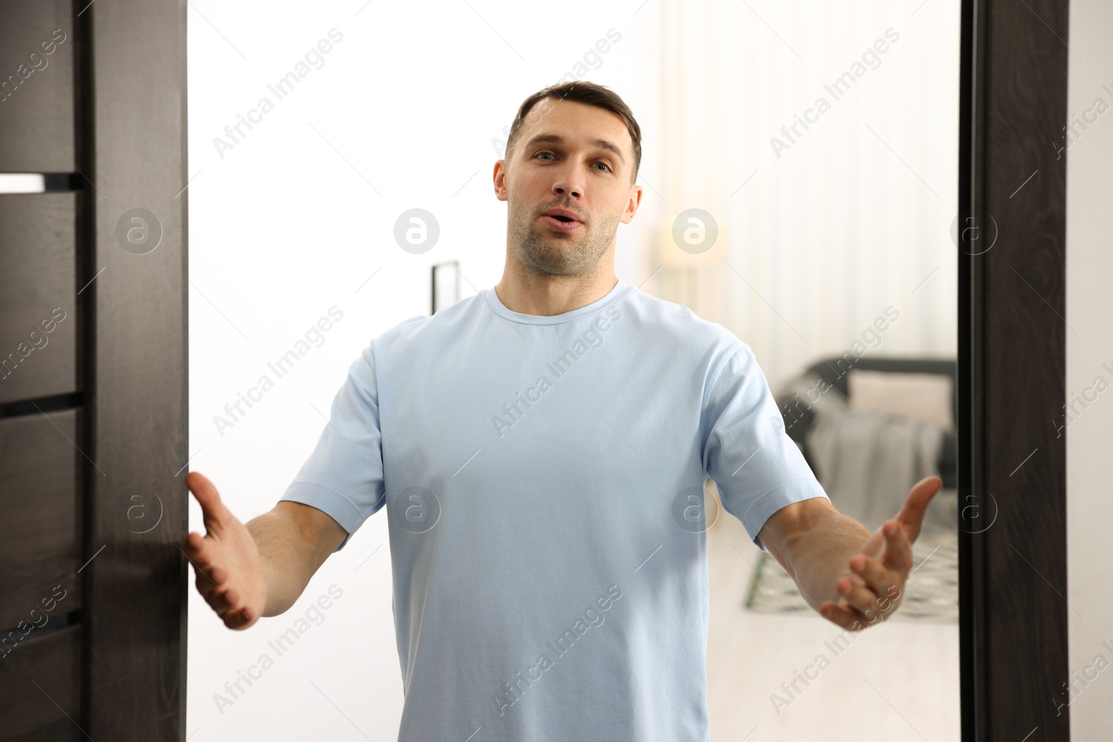 Photo of Cheerful man welcoming guests to his apartment