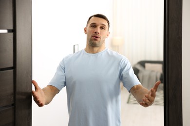 Photo of Cheerful man welcoming guests to his apartment