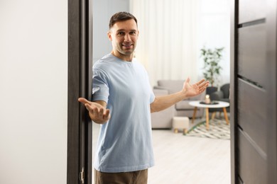 Photo of Cheerful man welcoming guests to his apartment