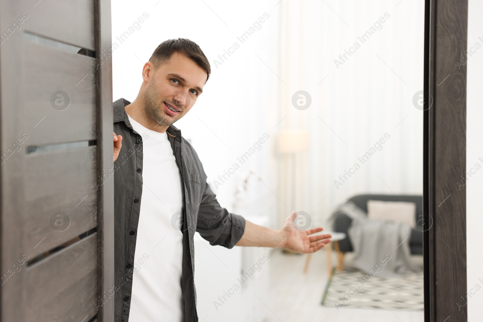 Photo of Cheerful man welcoming guests to his apartment. Space for text