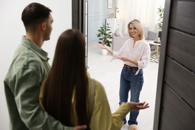 Photo of Happy woman welcoming friends to her apartment