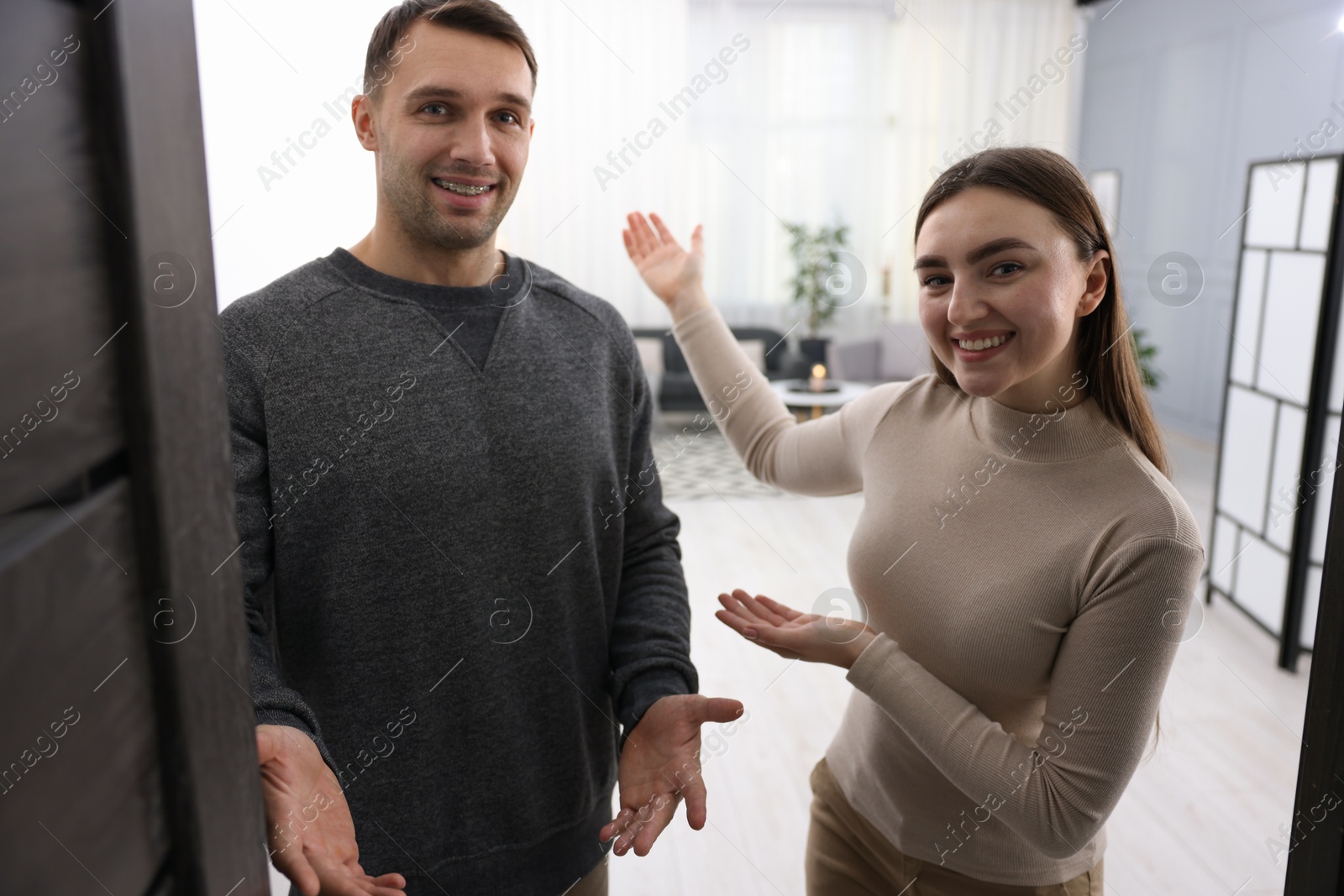 Photo of Happy couple welcoming guests to their apartment