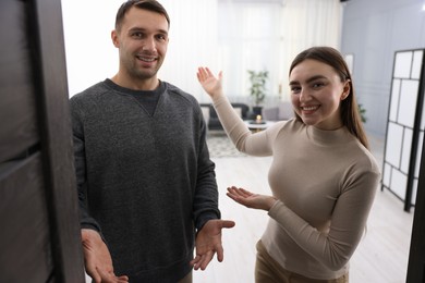 Photo of Happy couple welcoming guests to their apartment