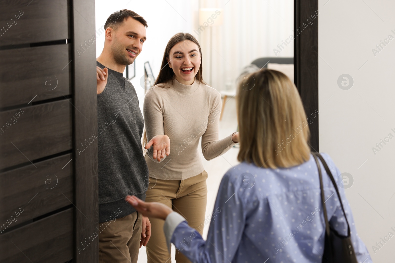 Photo of Lovely couple welcoming friend to their apartment