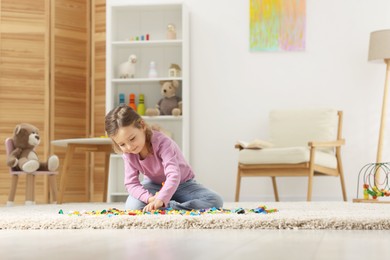 Photo of Cute girl playing with building blocks on floor at home. Space for text