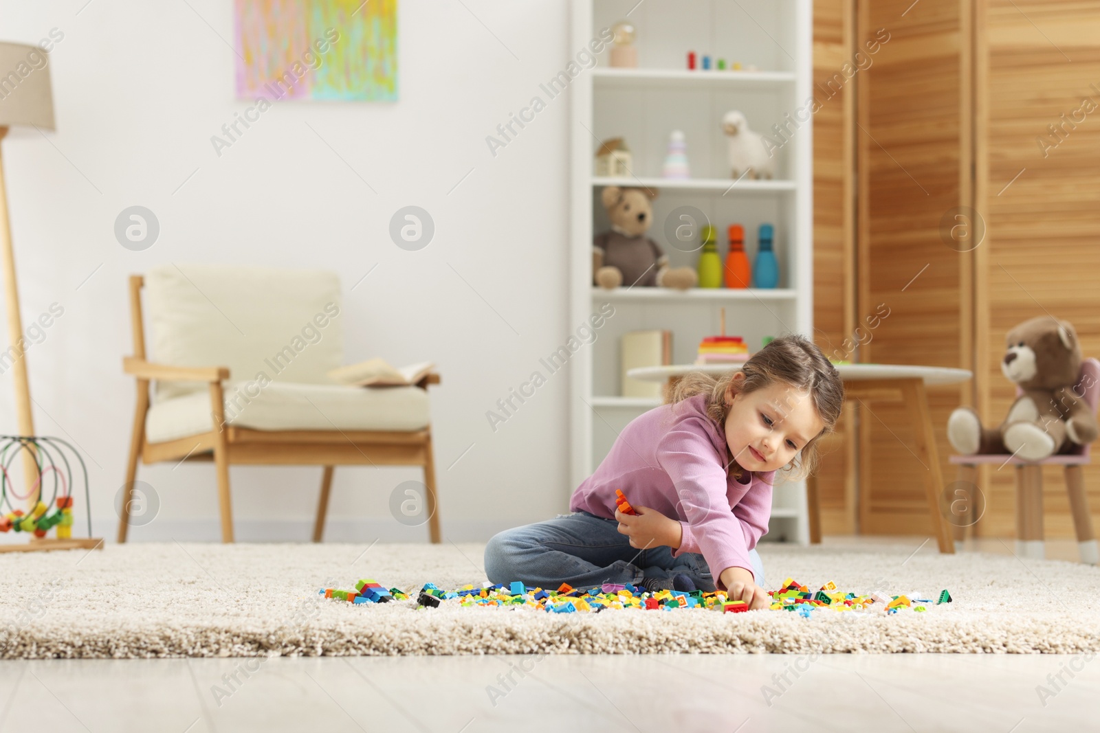 Photo of Cute girl playing with building blocks on floor at home. Space for text