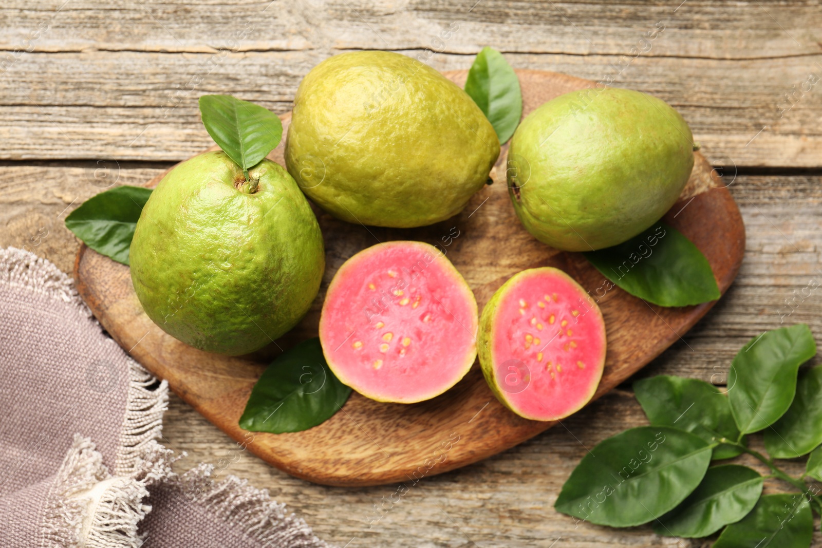 Photo of Fresh whole and cut guava fruits on wooden table, flat lay