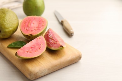 Photo of Fresh guava fruits on white wooden table, closeup. Space for text