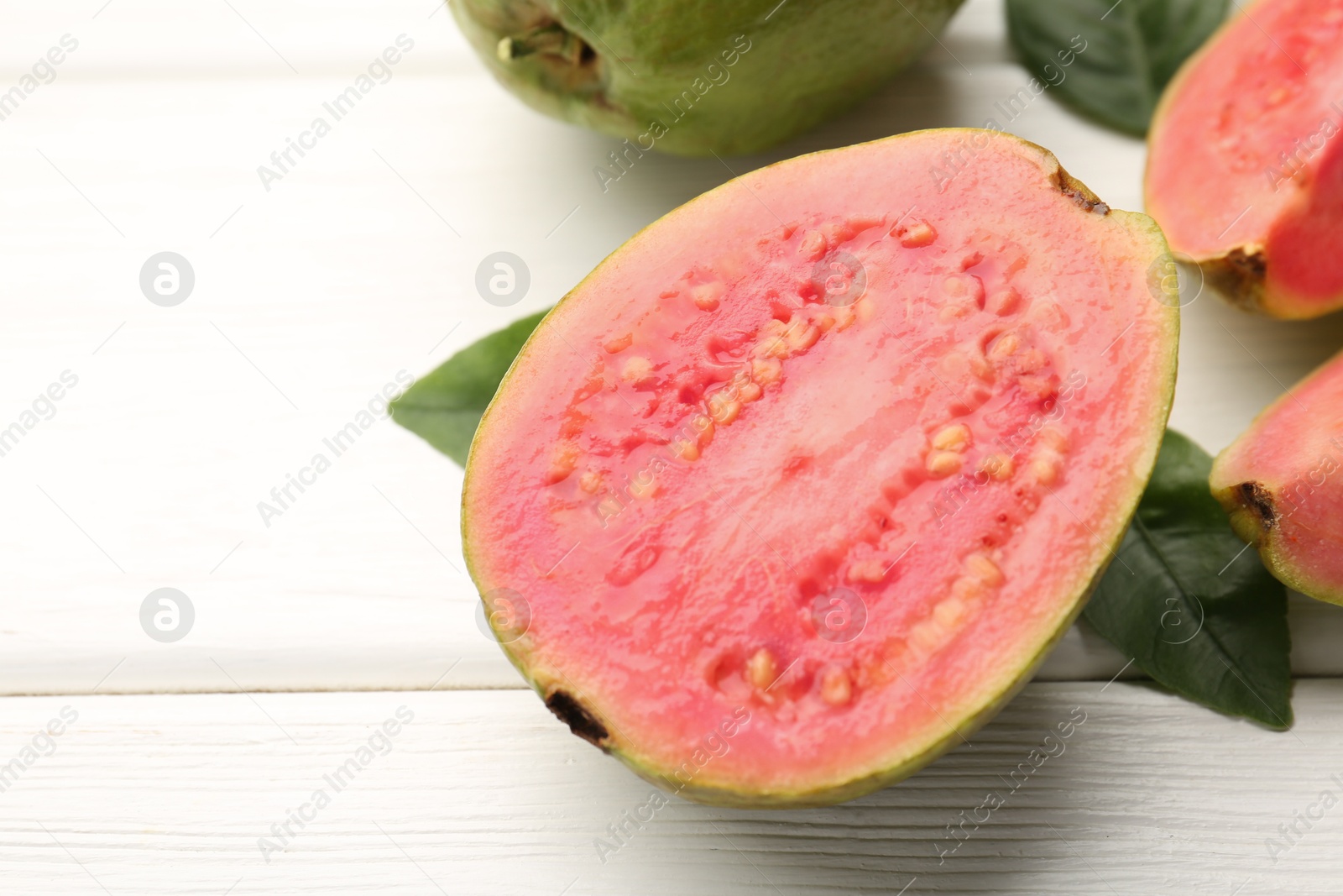 Photo of Half of fresh guava fruit on white wooden table, closeup. Space for text