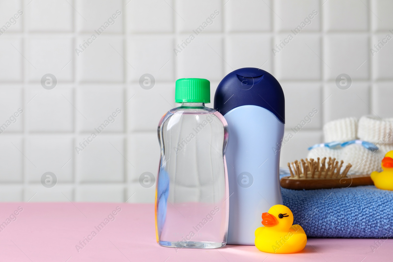 Photo of Baby oil and bath accessories on pink table. Space for text