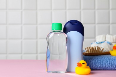 Photo of Baby oil and bath accessories on pink table. Space for text