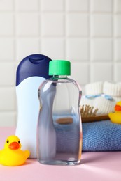 Photo of Baby oil and bath accessories on pink table, closeup