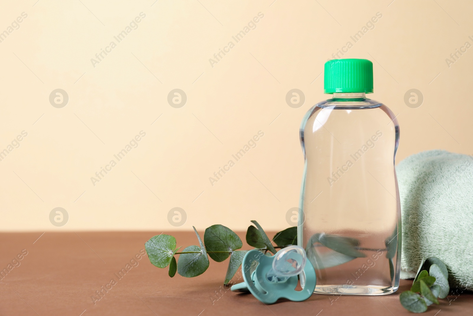 Photo of Baby oil, pacifier, towel and eucalyptus on color background, closeup. Space for text