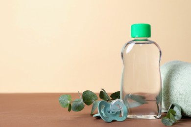 Photo of Baby oil, pacifier, towel and eucalyptus on color background, closeup. Space for text