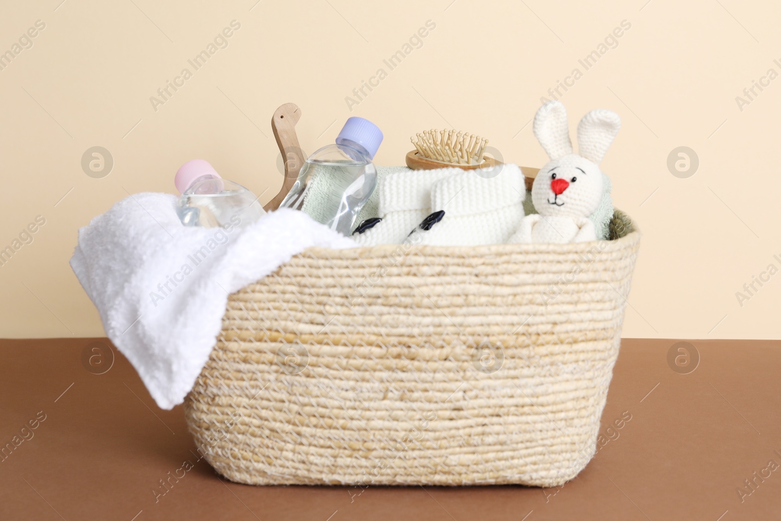 Photo of Baby oil and bath accessories in basket on color background