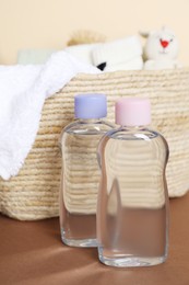 Photo of Baby oil and bath accessories in basket on color background, closeup