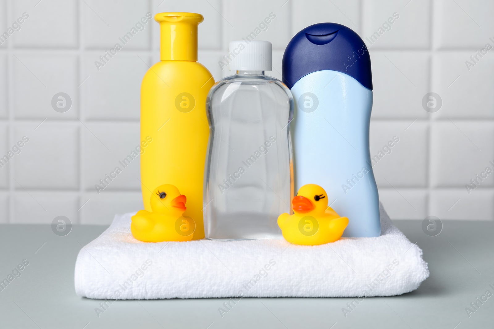 Baby oil and bath accessories on grey table Photo of Baby oil and bath accessories on grey table