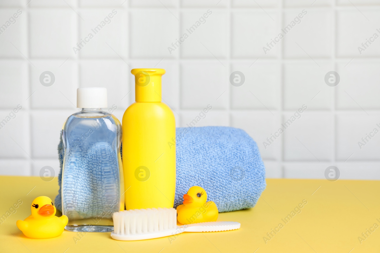 Photo of Baby oil and bath accessories on yellow table. Space for text