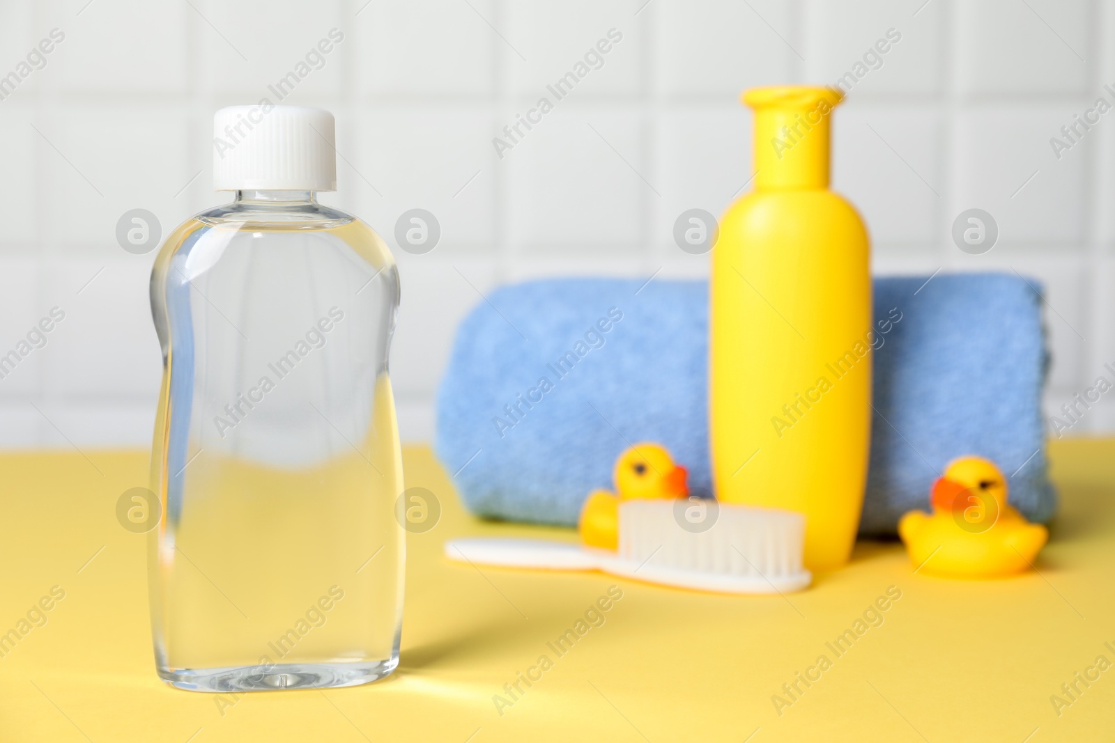 Baby oil and bath accessories on yellow table, selective focus Photo of Baby oil and bath accessories on yellow table, selective focus