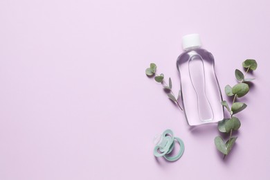 Photo of Baby oil, pacifier and eucalyptus on lilac background, top view. Space for text