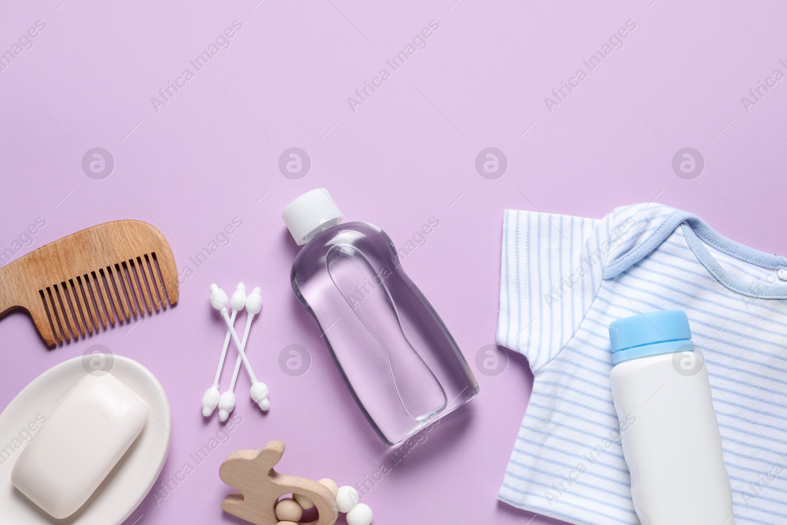 Photo of Baby oil, clothes and bath accessories on lilac background, flat lay