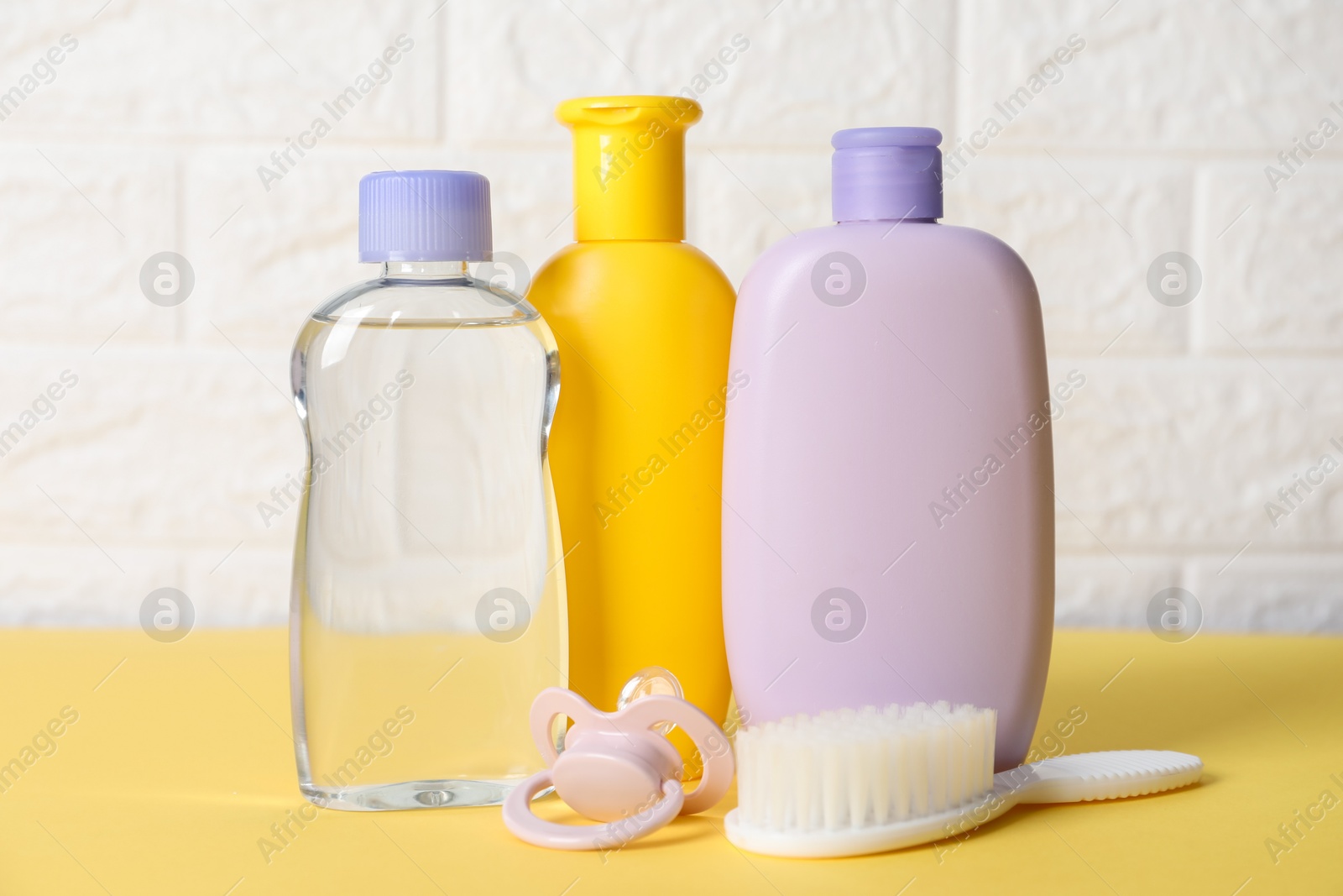 Photo of Baby oil and bath accessories on yellow table