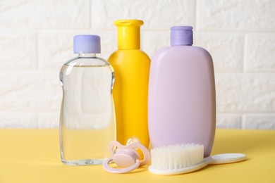 Photo of Baby oil and bath accessories on yellow table