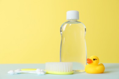 Photo of Baby oil, rubber duck, brush and cotton swabs on color background. Space for text