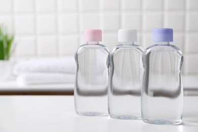 Photo of Baby oil in bottles on white table against blurred background. Space for text