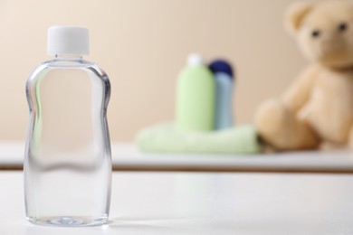 Photo of Baby oil in bottle on white table against blurred background. Space for text