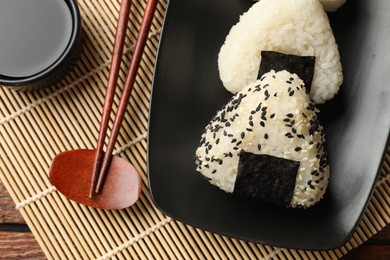 Photo of Rice balls (onigiri), soy sauce and chopsticks on table, flat lay. Traditional Japanese dish