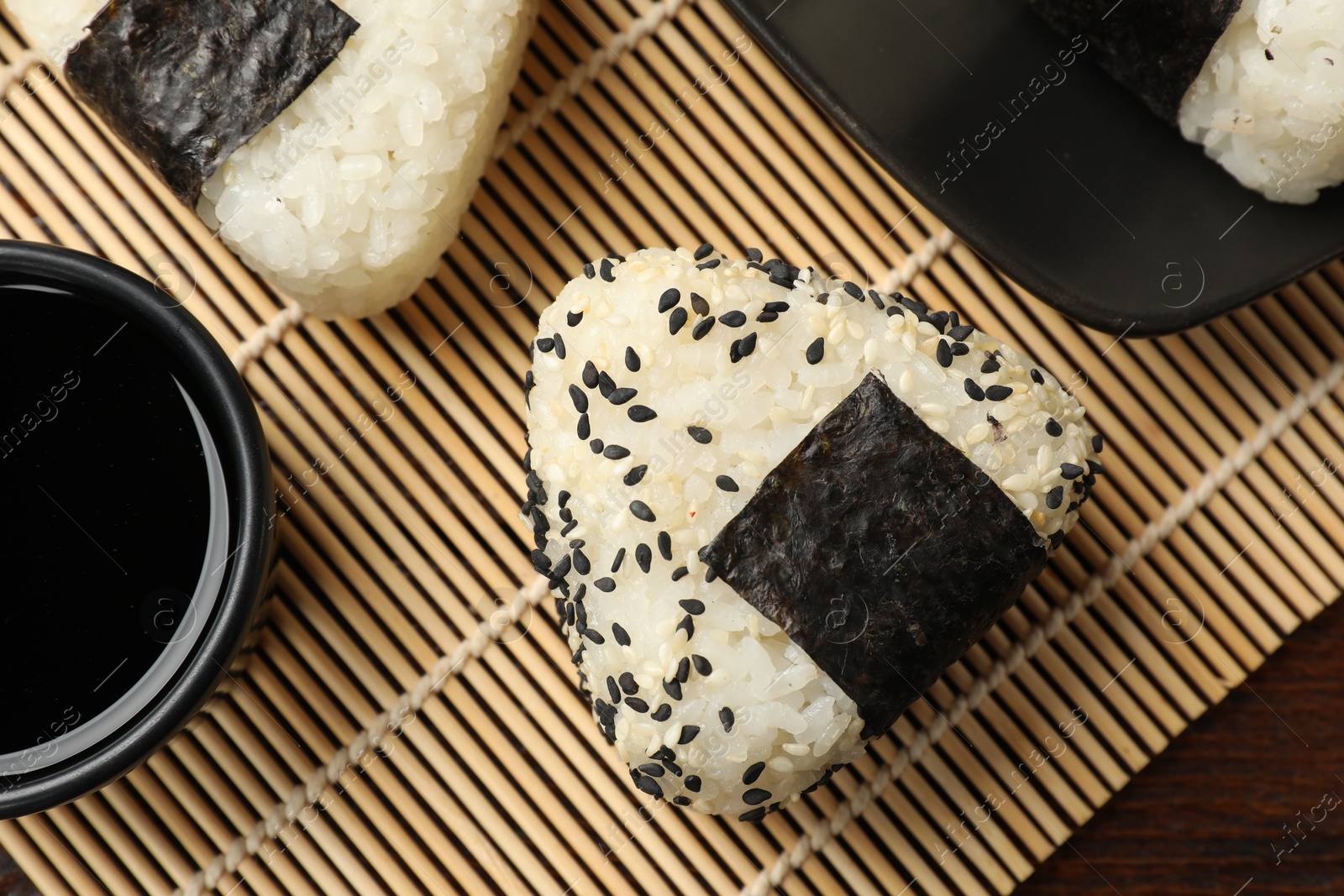 Photo of Rice balls (onigiri) and soy sauce on table, flat lay. Traditional Japanese dish