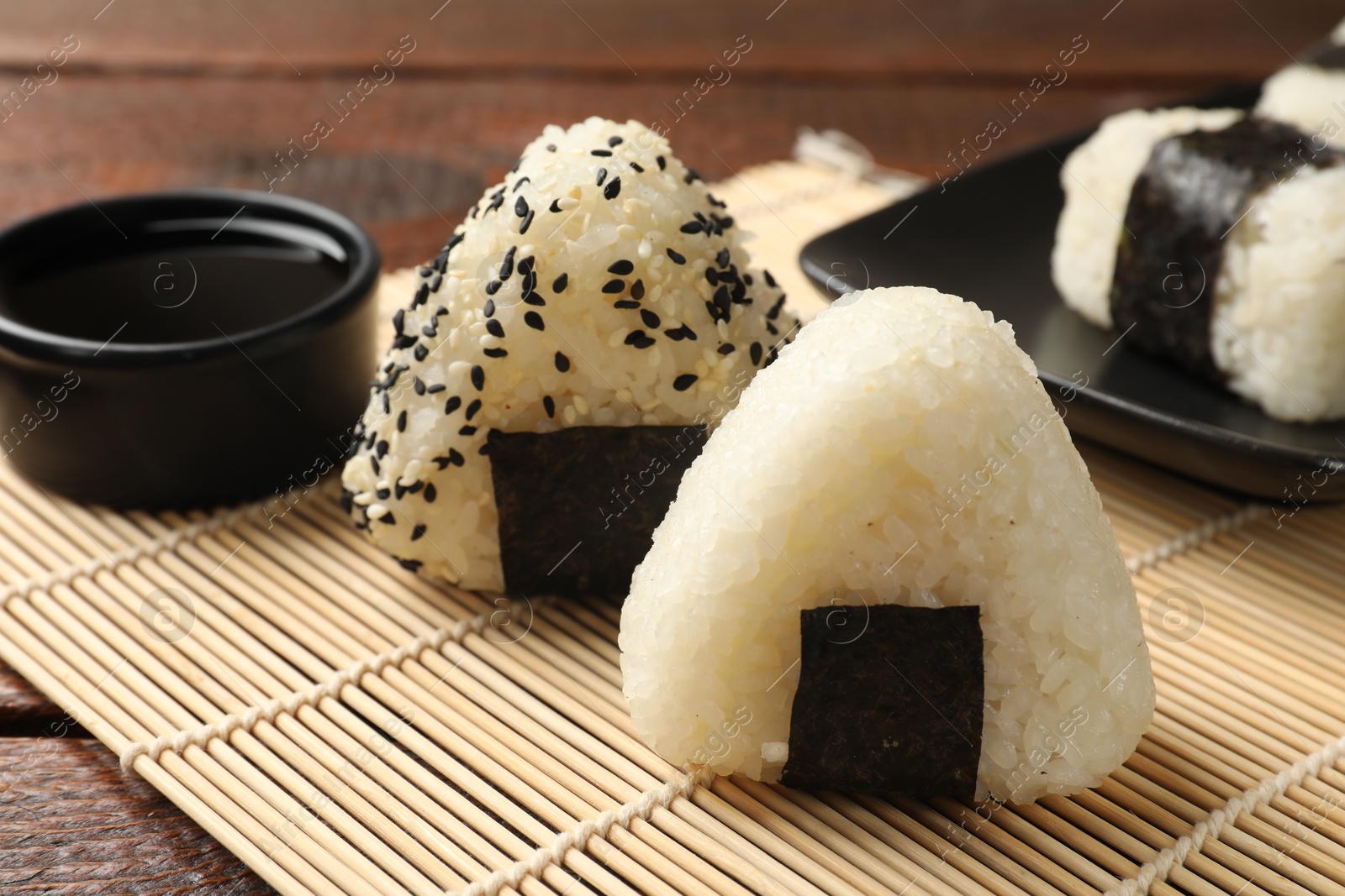 Photo of Rice balls (onigiri) and soy sauce on wooden table, closeup. Traditional Japanese dish