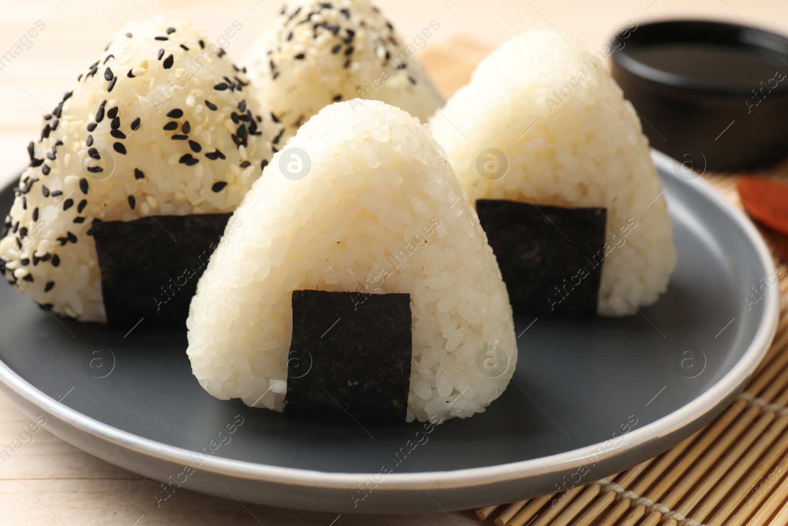 Photo of Rice balls (onigiri) and soy sauce on table, closeup. Traditional Japanese dish