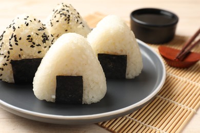 Photo of Rice balls (onigiri), soy sauce and chopsticks on wooden table, closeup. Traditional Japanese dish