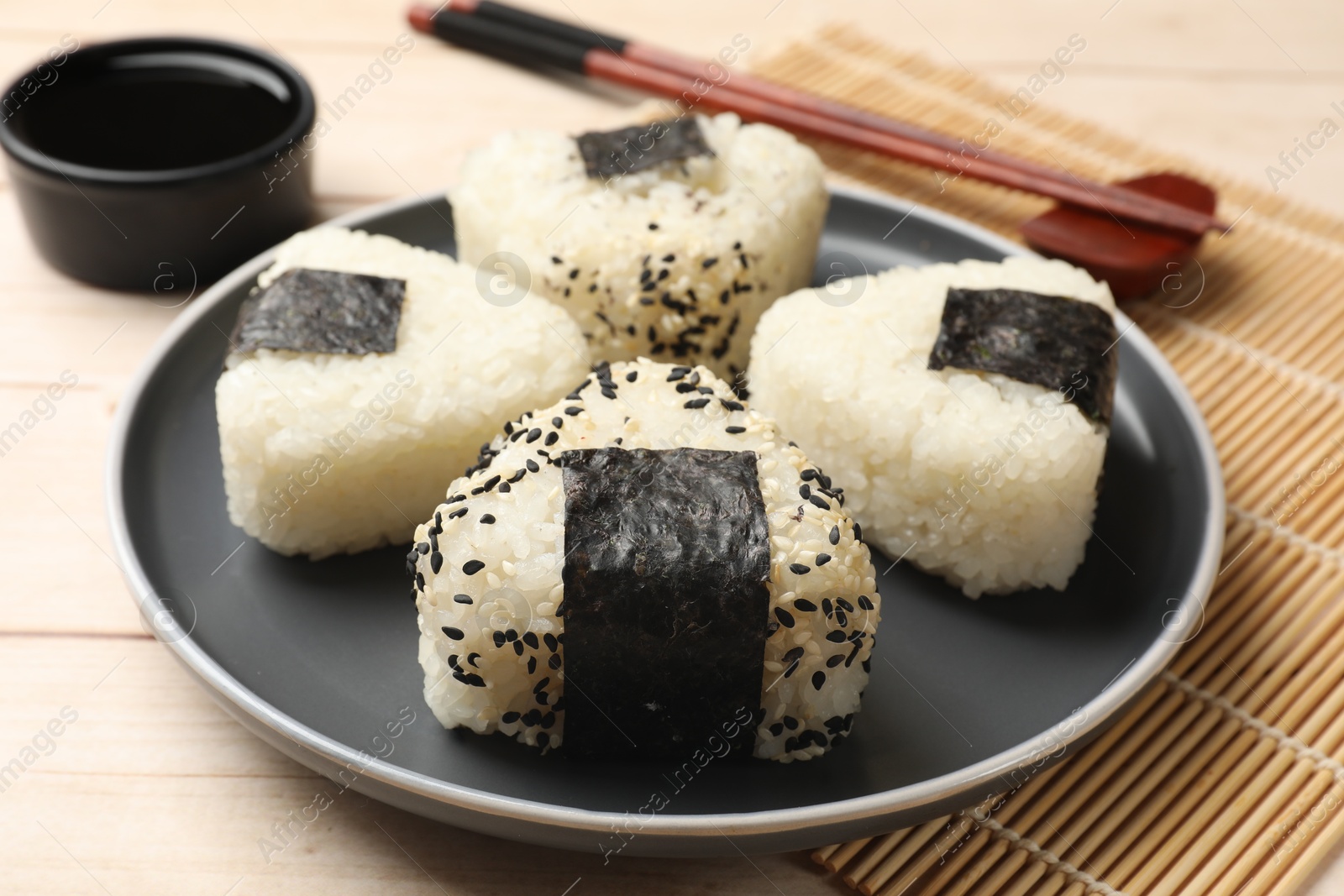 Photo of Rice balls (onigiri), soy sauce and chopsticks on wooden table, closeup. Traditional Japanese dish