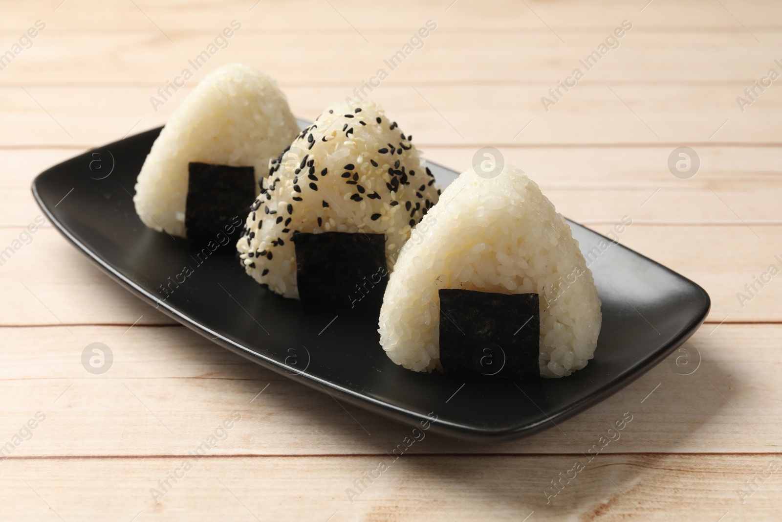 Photo of Rice balls (onigiri) on wooden table, closeup. Traditional Japanese dish