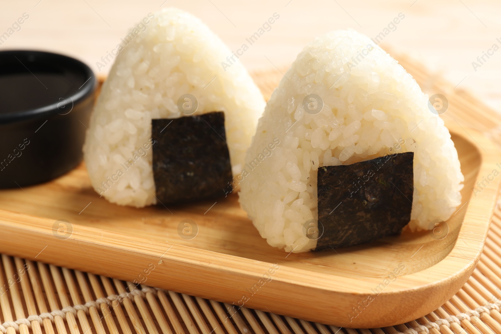 Photo of Rice balls (onigiri) and soy sauce on table, closeup. Traditional Japanese dish