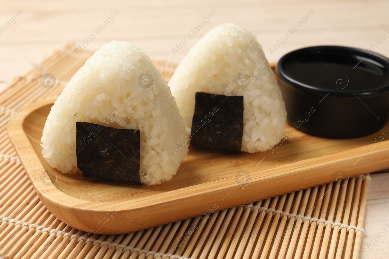 Photo of Rice balls (onigiri) and soy sauce on table, closeup. Traditional Japanese dish