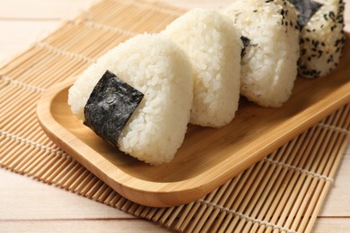 Photo of Rice balls (onigiri) on wooden table, closeup. Traditional Japanese dish