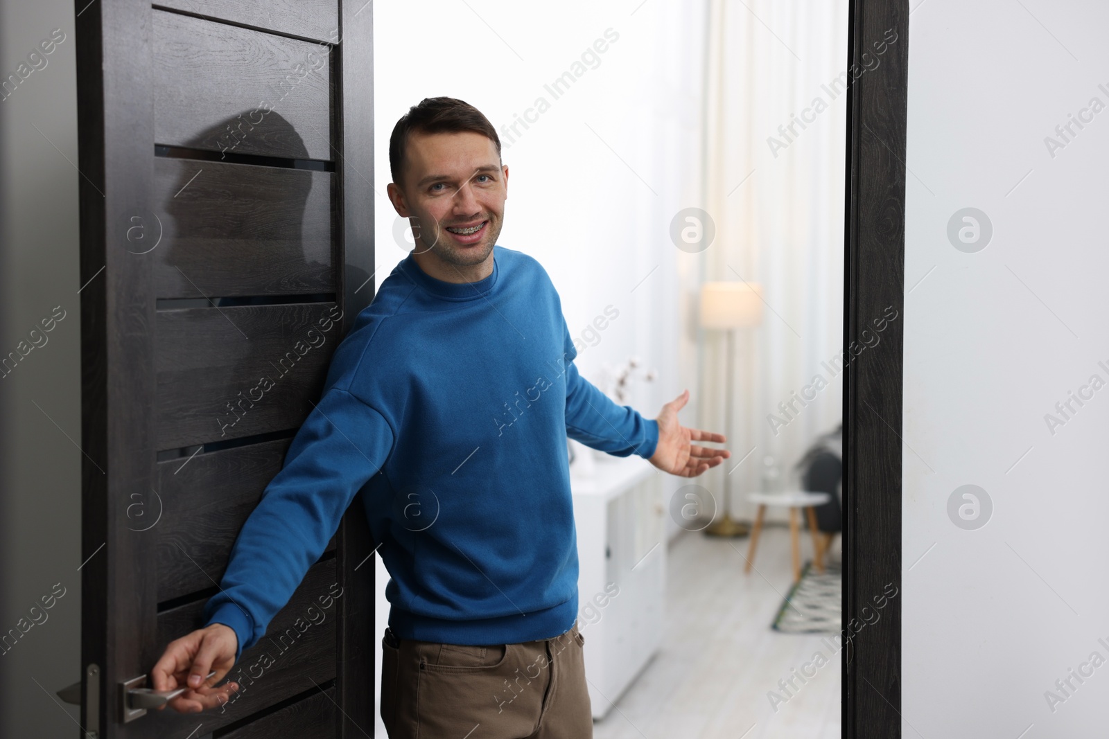 Photo of Cheerful man welcoming guests to his apartment