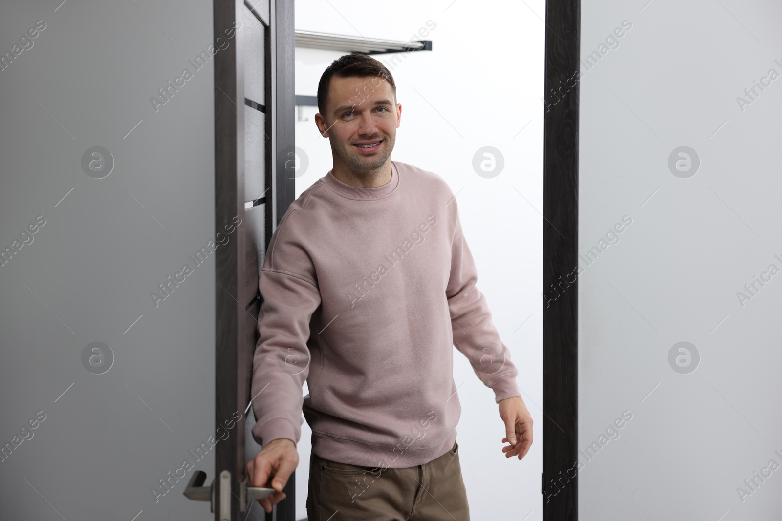 Photo of Cheerful man welcoming guests to his apartment