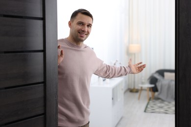 Photo of Cheerful man welcoming guests to his apartment